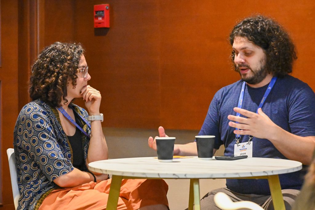 Two WordCamp Asia attendees sit at a small table having a focused one-on-one conversation during Contributor Day.
