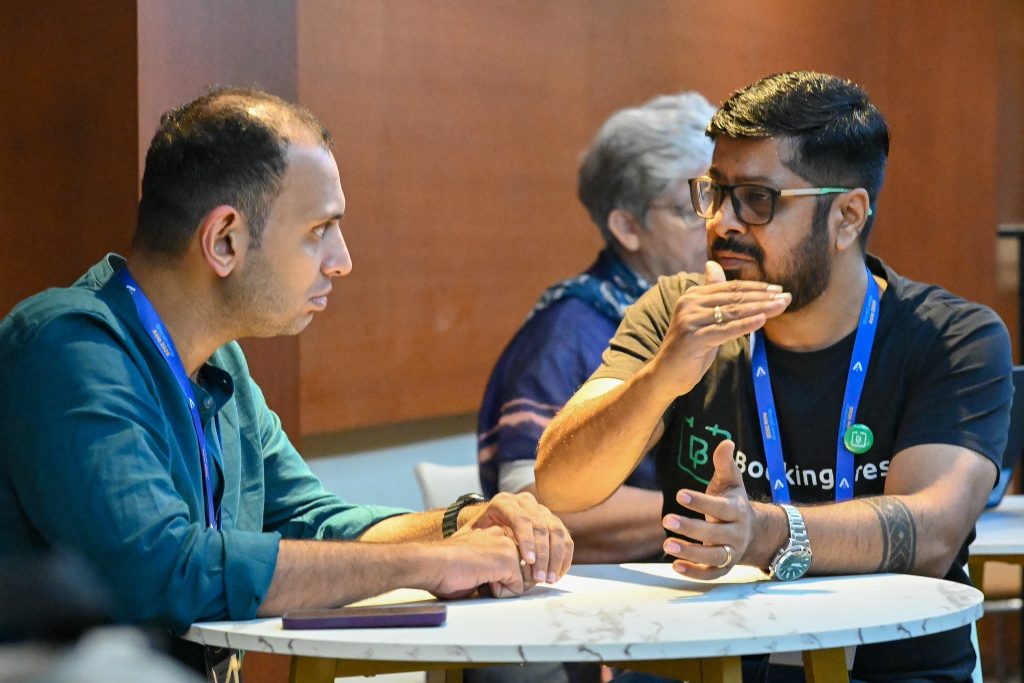 Two WordCamp Asia attendees engage in an animated discussion at a small table during Contributor Day.