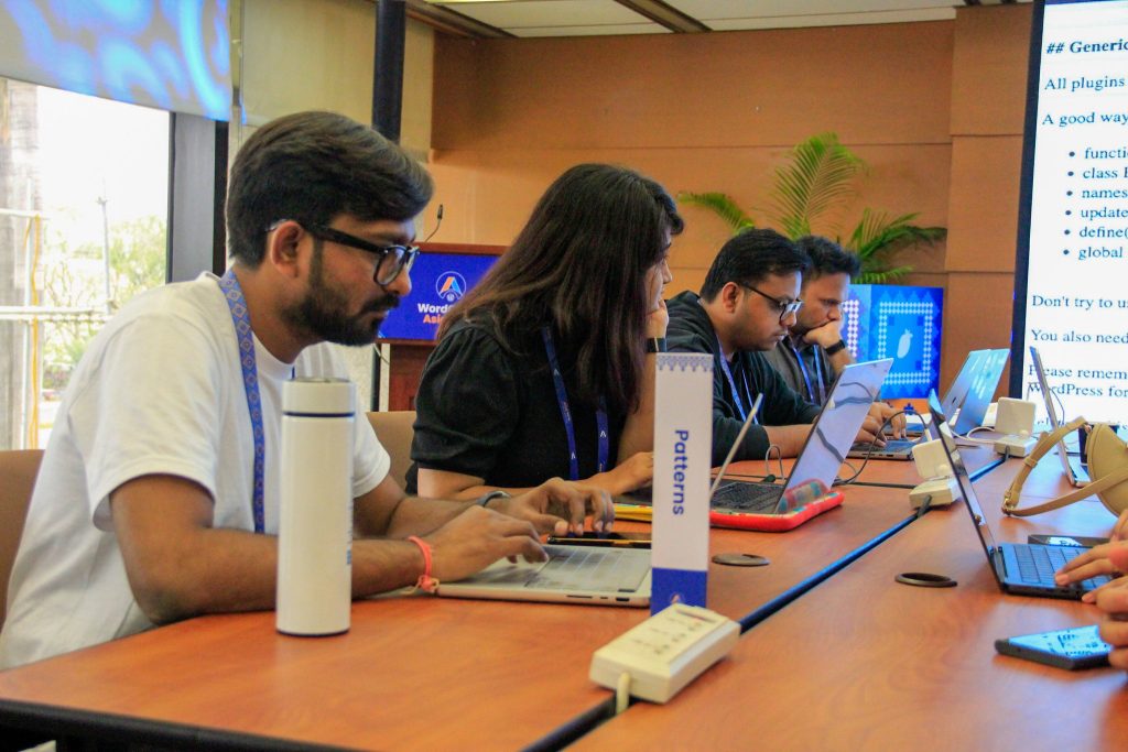 Contributors working on laptops at the Patterns table during WordCamp Asia 2025 Contributor Day.