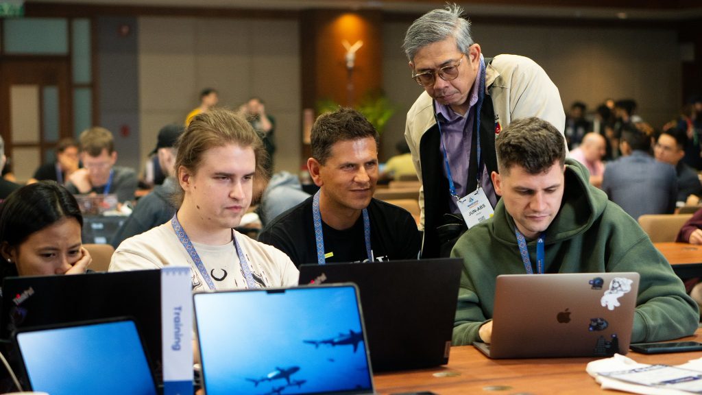 Contributors working together at the Training table while a mentor provides guidance during WordCamp Asia 2025.